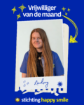 Portretfoto van Lindsay ten Caat, vrijwilliger bij Stichting Happy Smile since 2020, in een polaroidkader met haar naam in handschrift. Op de achtergrond het blauwe Happy Smile-blauw met gele sterren en het logo van de stichting onderaan.